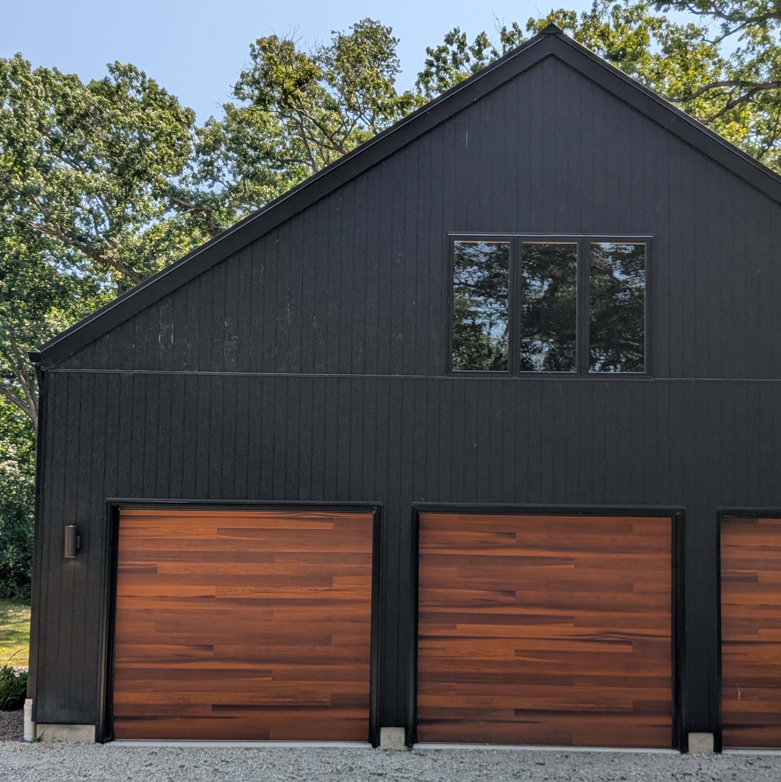 Window above 3 wooden garage doors on a large A-frame garage