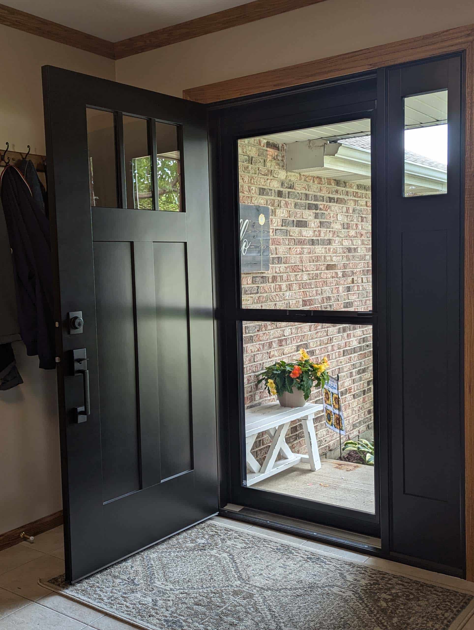 Open black modern residential front door with a glass screen door