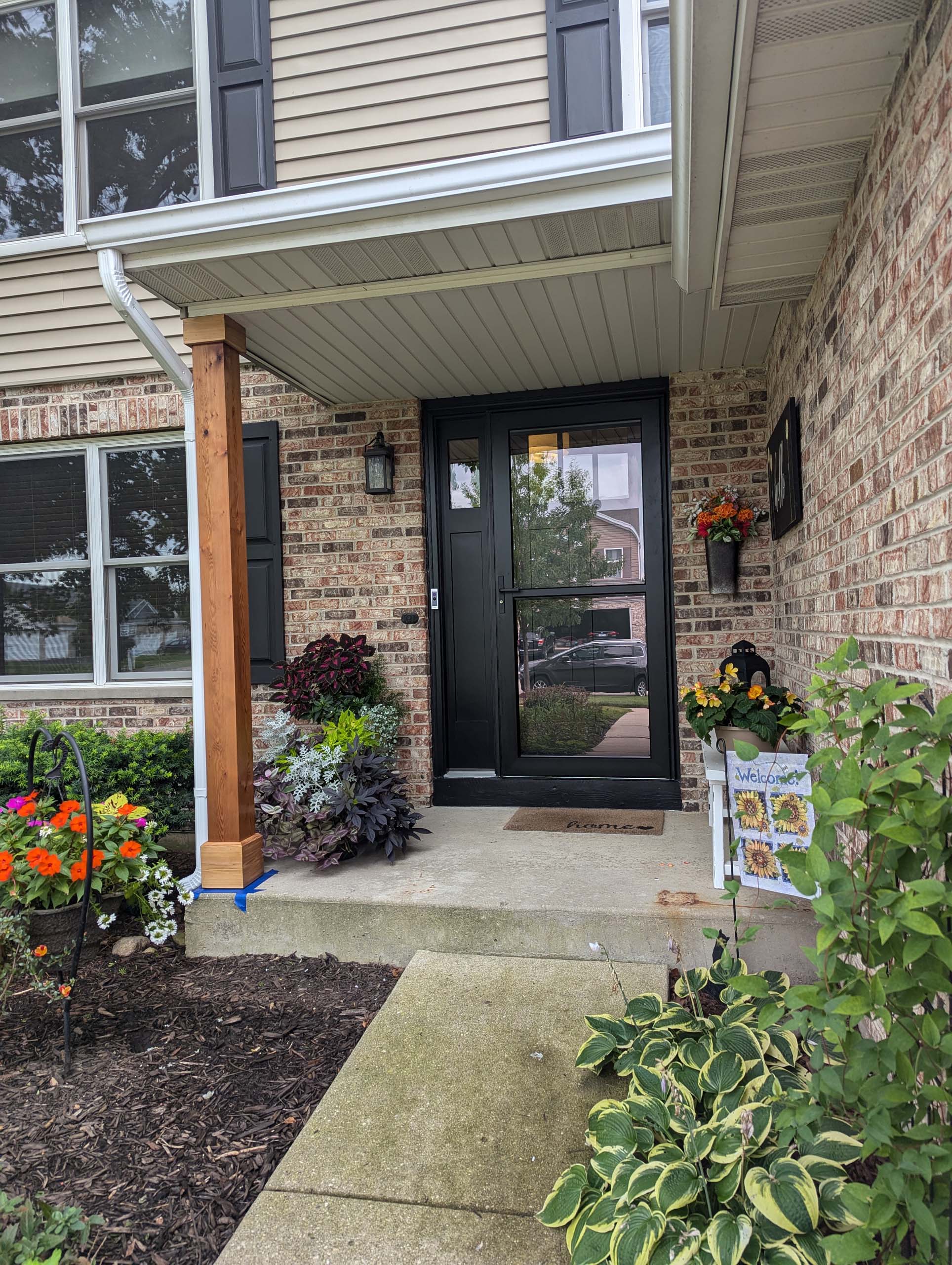 Open black modern residential front door with a glass screen door